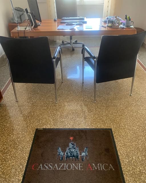 Ufficio di Cassazione Amica a Piazzale Clodio, postazione di lavoro con scrivania in legno e zerbino con logo dell'azienda